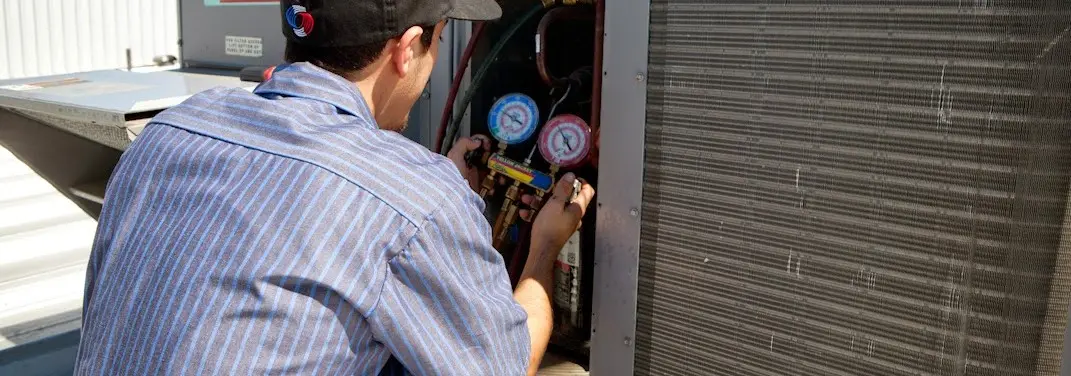 HVAC technician servicing a condenser unit in New Windsor